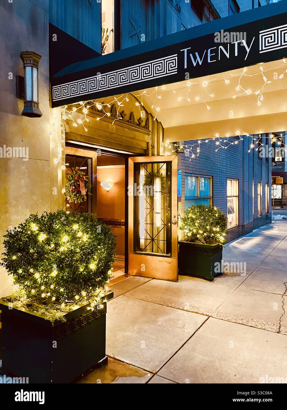 Scintillanti luci di vacanza sotto la tenda Art Deco di un alto edificio di Manhattan con una squisita architettura vista dal marciapiede di East 35th Street tra Park Avenue e Madison Avenue. - Immagine stock catturata con smartphone