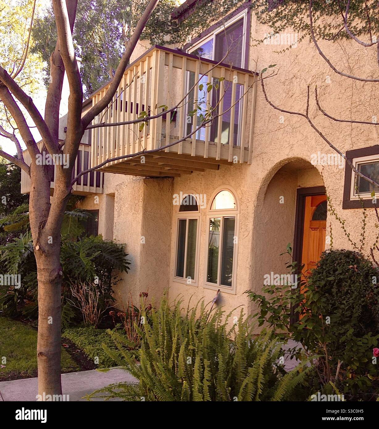 Entrata ad arco in un condominio della California del Sud con lussureggianti giardini. Iconica costruzione in stucco con balcone affacciato sugli alberi. Foto Stock