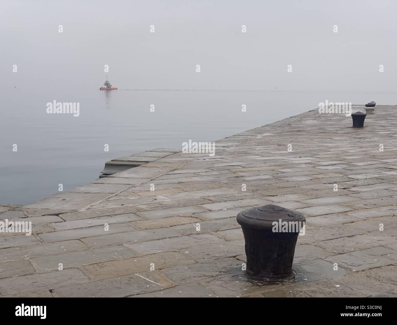 Tug e Pier in una giornata invernale nuvolosa. - Immagine stock catturata con smartphone