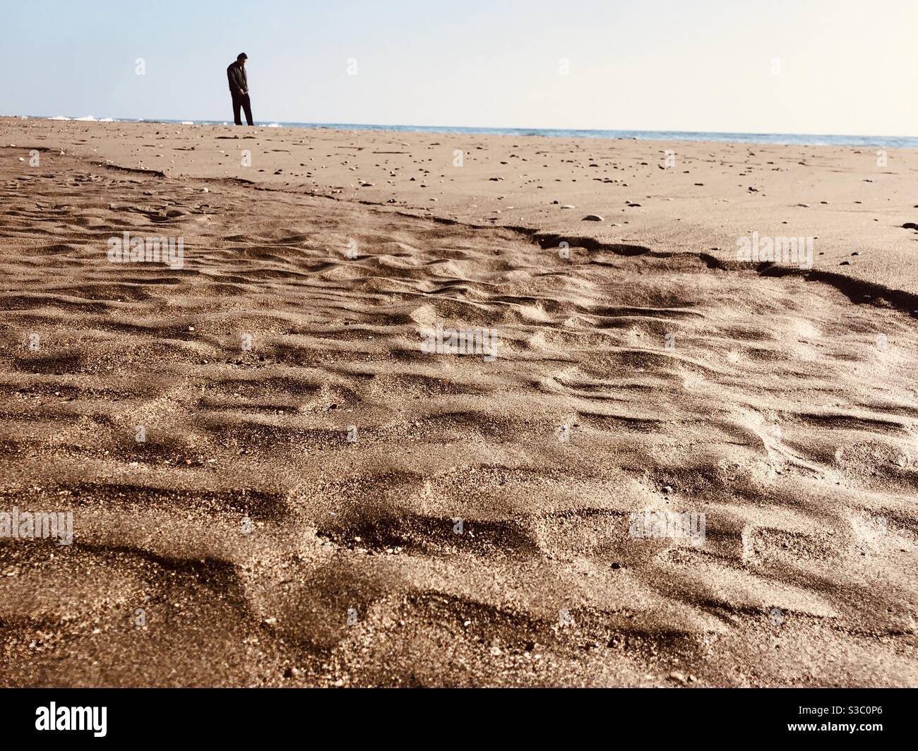Uomo in piedi su una spiaggia vuota - Immagine stock catturata con smartphone