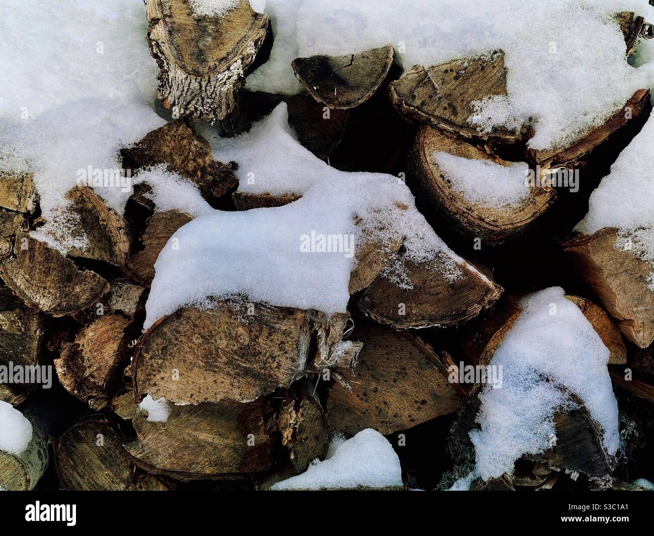Un mucchio di legna da ardere parzialmente coperto di neve Foto Stock