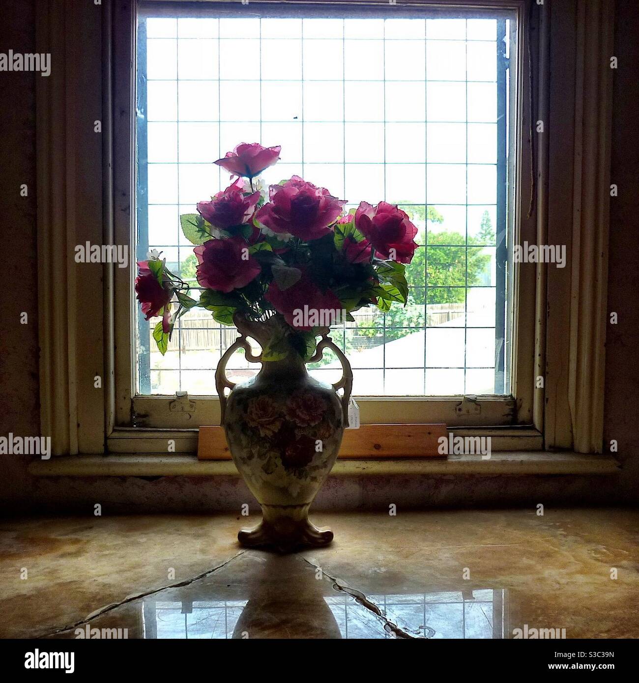 Fiori falsi in vaso di ceramica su tavolo di marmo con il riflessione dell'ombra dalla finestra Foto Stock