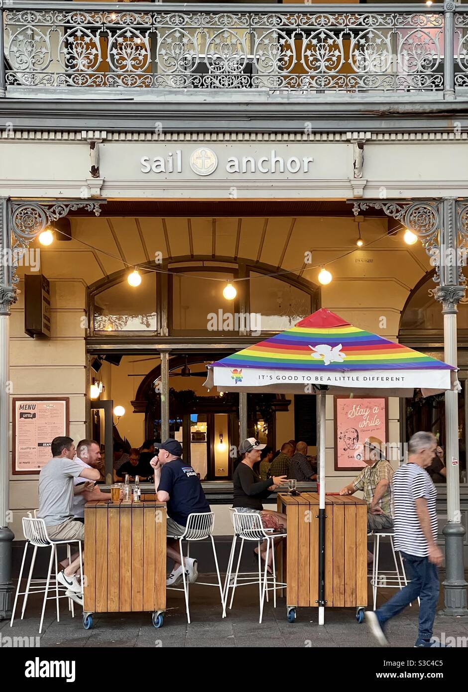 Uomini che bevono birra all'aperto sotto un ombrello arcobaleno all'esterno L'hotel Sail and Anchor e il pub Fremantle Western Australia Foto Stock