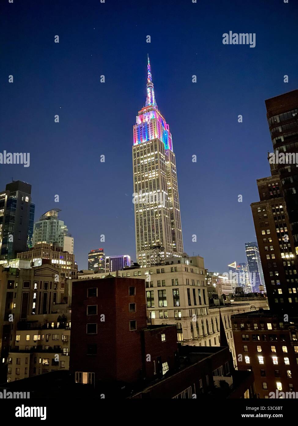 New Years Eeve mette in luce luci multicolore sulla cima dell'Empire state Building a Midtown Manhattan contro le sagome di altri grattacieli di New York City, USA Foto Stock