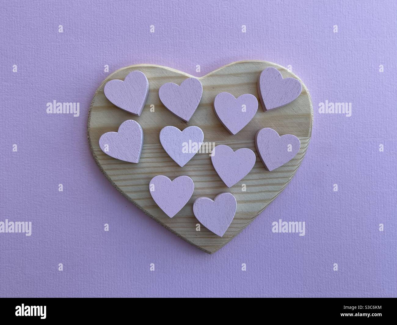 Concetto di amore con cuori di legno rosa su un cuore di legno Foto Stock