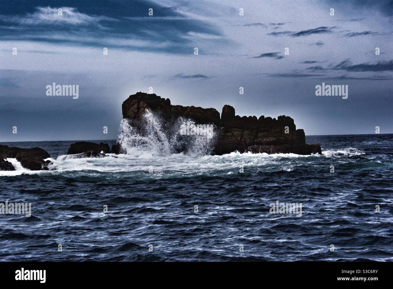 Drammatica scena del mare con le onde dell'Oceano Atlantico che si infrangono contro la roccia nera in una foto di moody fuori delle isole Scilly, Cornovaglia, Inghilterra, Regno Unito Foto Stock