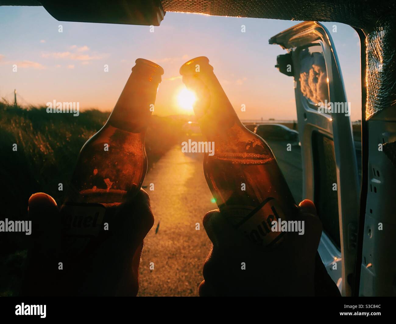 Guardando il tramonto dal retro di un camper con bottiglie di birra. Grazie. Festeggiando Foto Stock