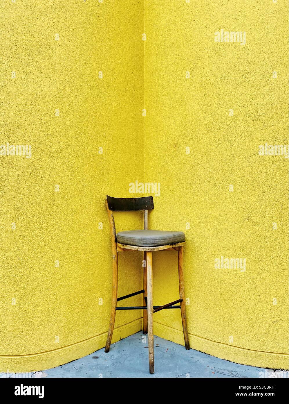Si tratta letteralmente di un posto a sedere ad angolo, una sedia in un angolo giallo di un edificio Foto Stock