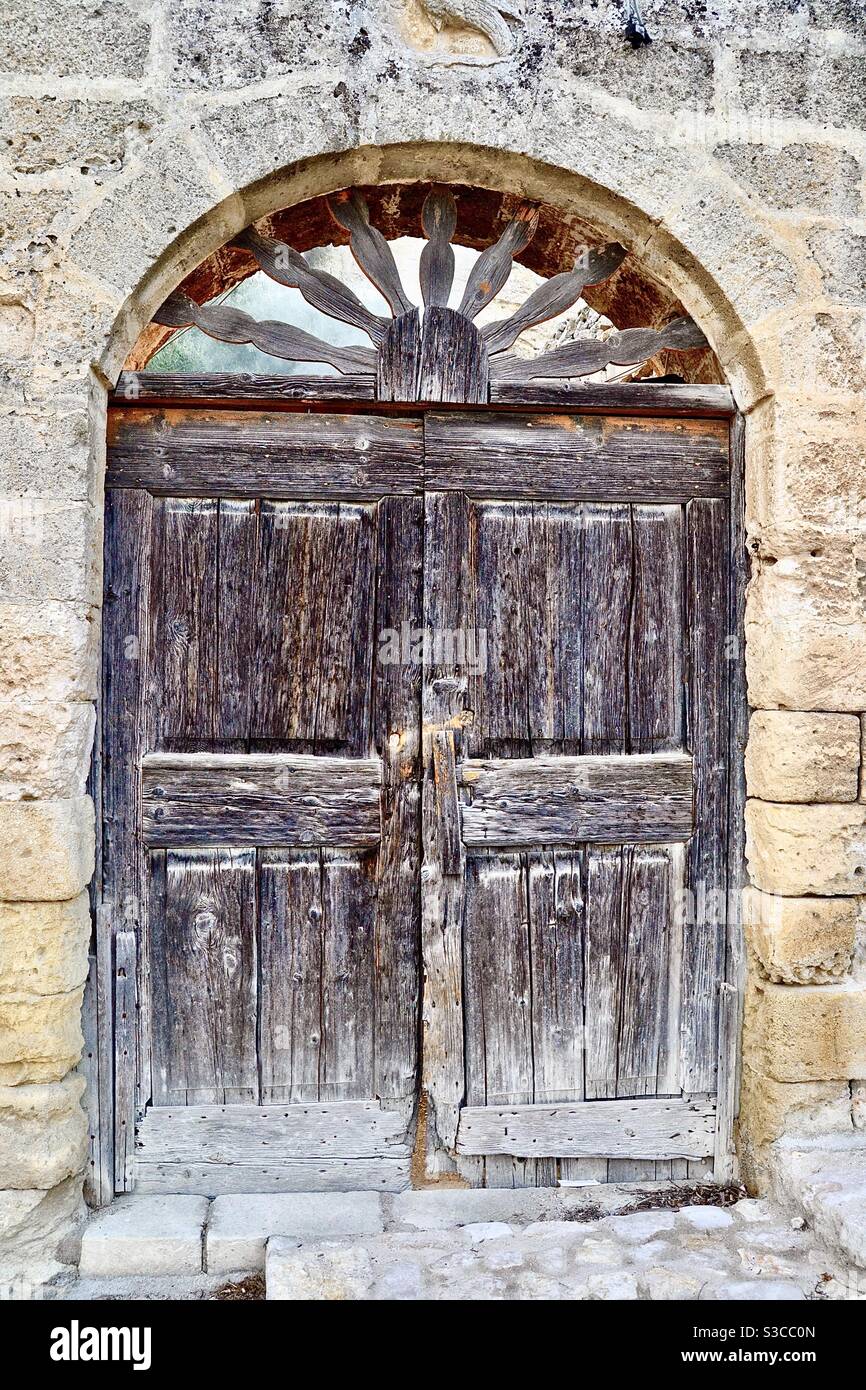 Antica e spessa porta in legno con pannello decorativo in una Semicerchio  scolpito sopra nella vecchia roccia storica a sud di Metairie Italia in  estate Foto stock - Alamy
