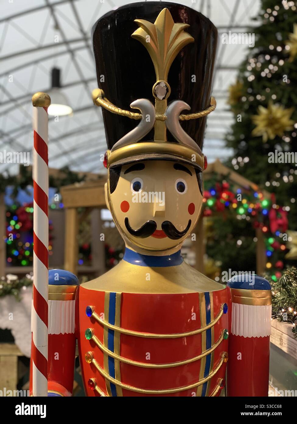 Un grande soldato giocattolo decorazioni natalizie in piedi in un negozio di Natale mostra con rosate guance rosse dipinte, baffi e indossare la sua uniforme lucido e cappello soldato Foto Stock