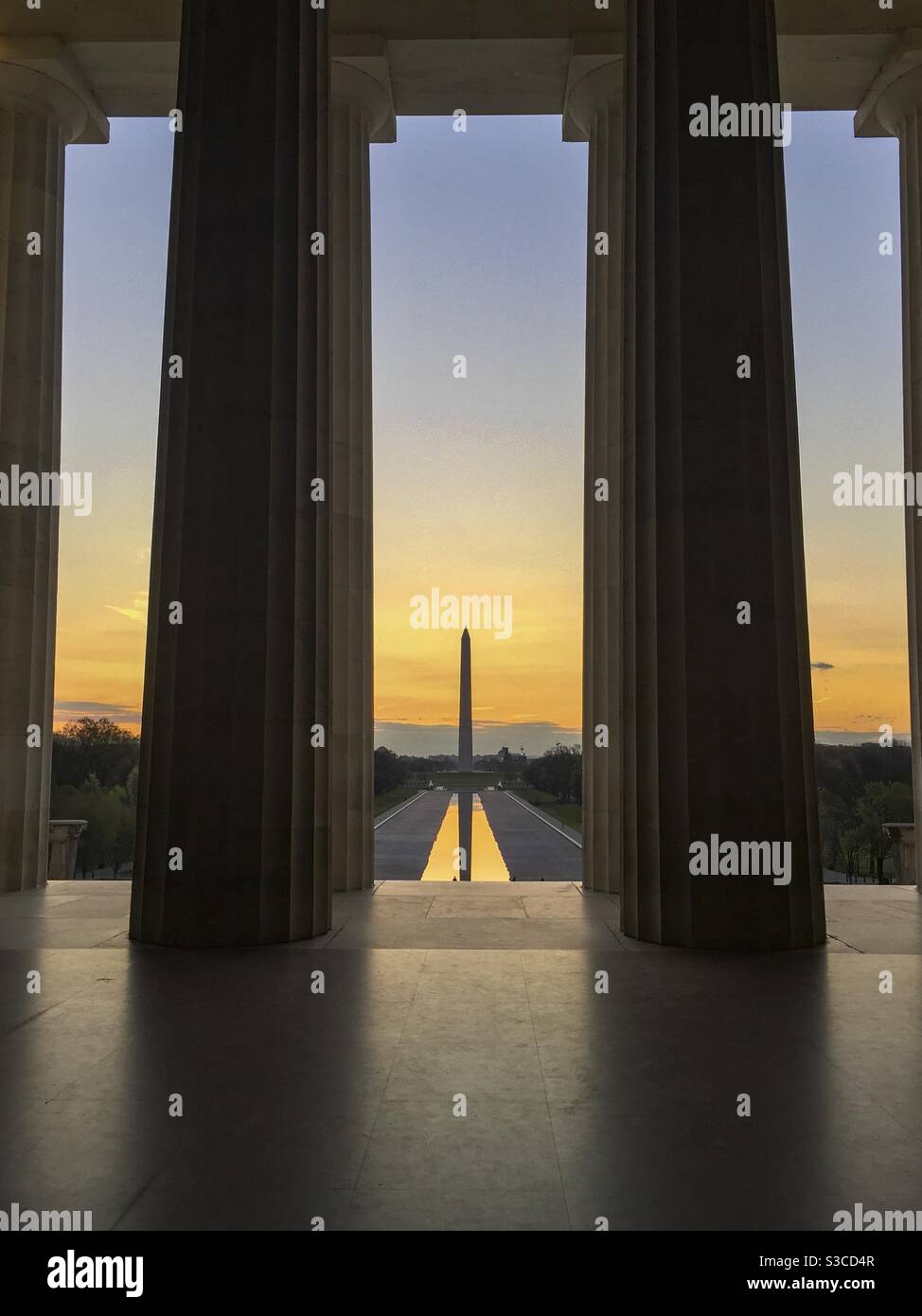 Il sole sorge sopra il monumento di Washington e il Reflecting Pool di Washington DC, come si vede dall'interno del Lincoln Memorial. - Immagine stock catturata con smartphone