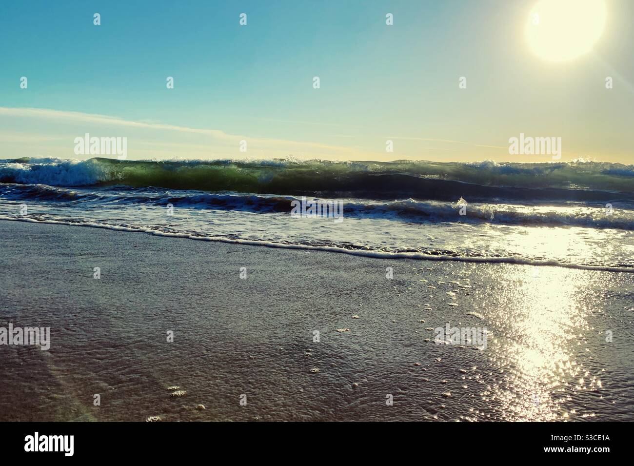 Onde arricciarsi e schiacciarsi sulla spiaggia di sabbia in un pomeriggio soleggiato nella California del sud. Foto Stock