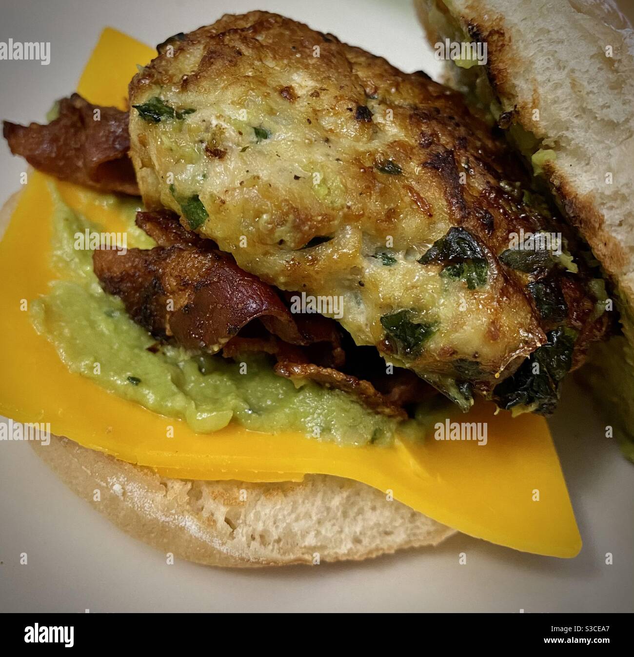 Hamburger di spinaci con avocado di pollo fatto in casa con formaggio e pancetta su pane artigianale tostato. Foto Stock