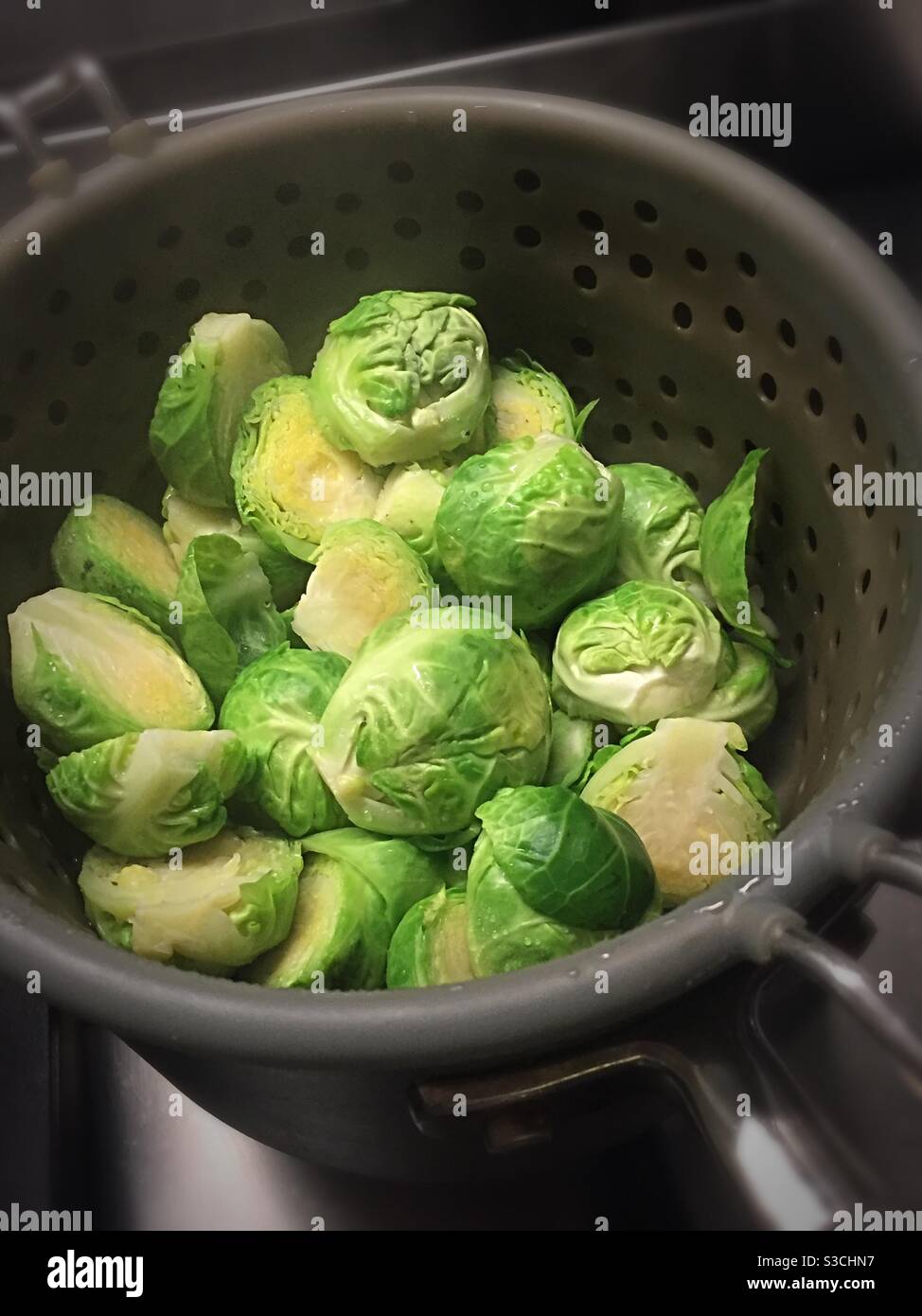 Brussel fresco crudo germogli cottura su un piano cottura residenziale, Stati Uniti Foto Stock
