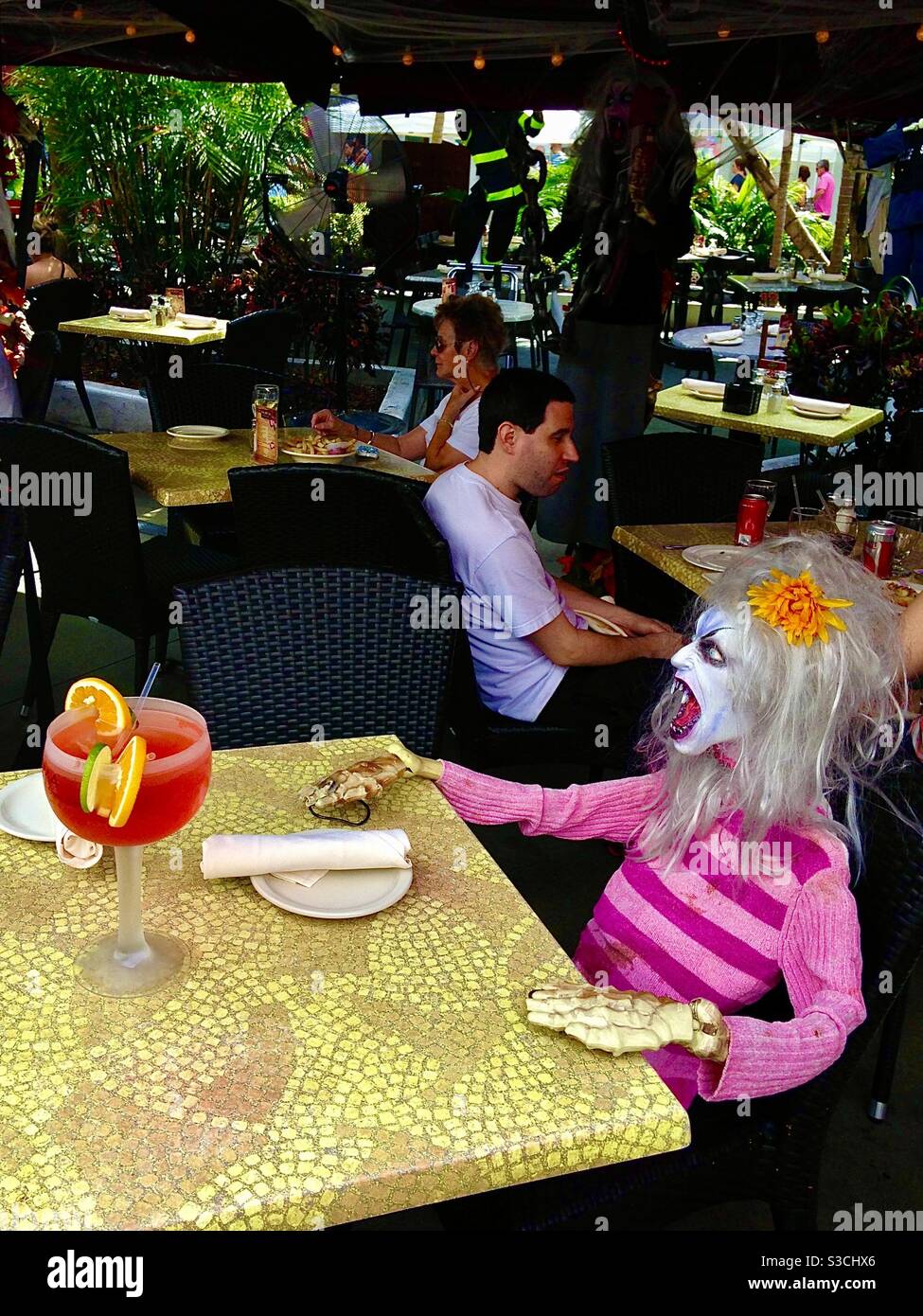 Voglio il servizio e lo voglio subito! Il manichino spaventoso sembra dirlo mentre gode di un cocktail tropicale colorato in un ristorante affollato a South Beach Miami, Florida, USA Foto Stock