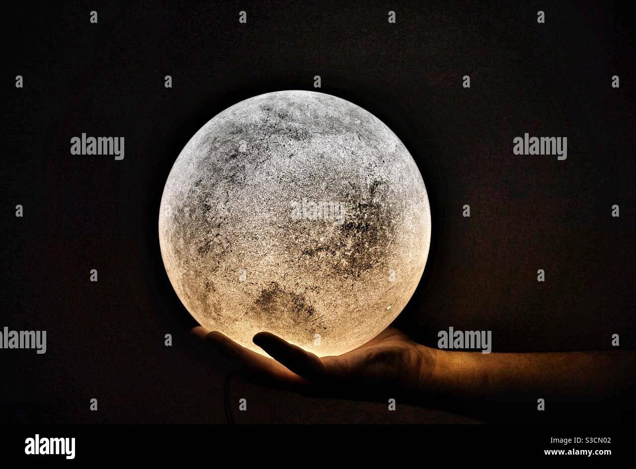 Una mano di un uomo che tiene una lampada a forma di una luna dove c'è un  contrasto tra caldo e. illuminazione fredda Foto stock - Alamy