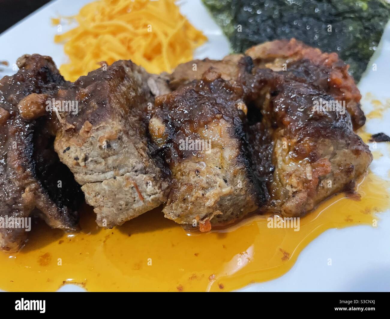 Succulenta bistecca di maiale arrosto con burro e salsa all'aceto, formaggio e alghe sul lato. Foto Stock