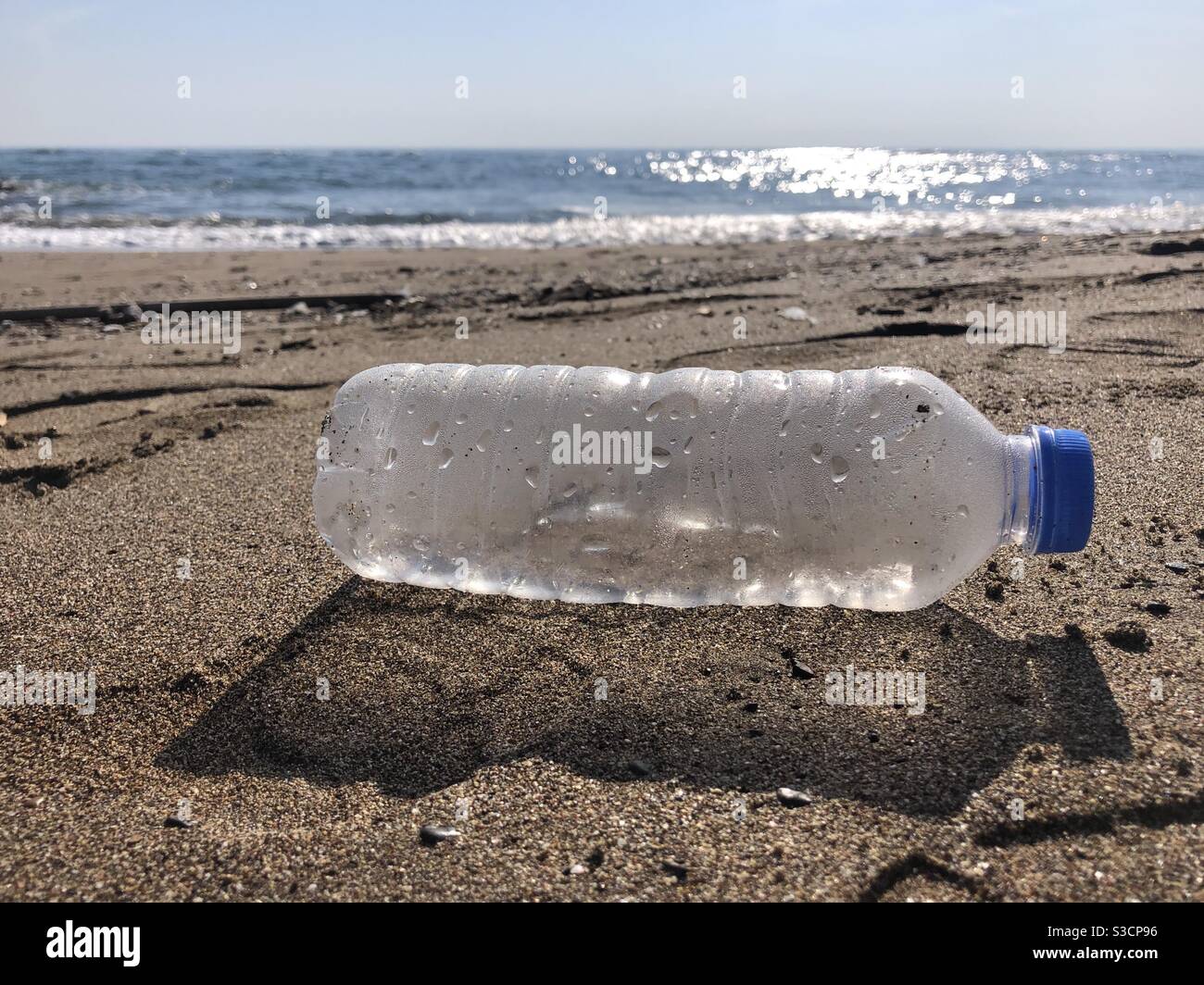 Bottiglia di plastica lasciata sulla spiaggia causando inquinamento - Immagine stock catturata con smartphone