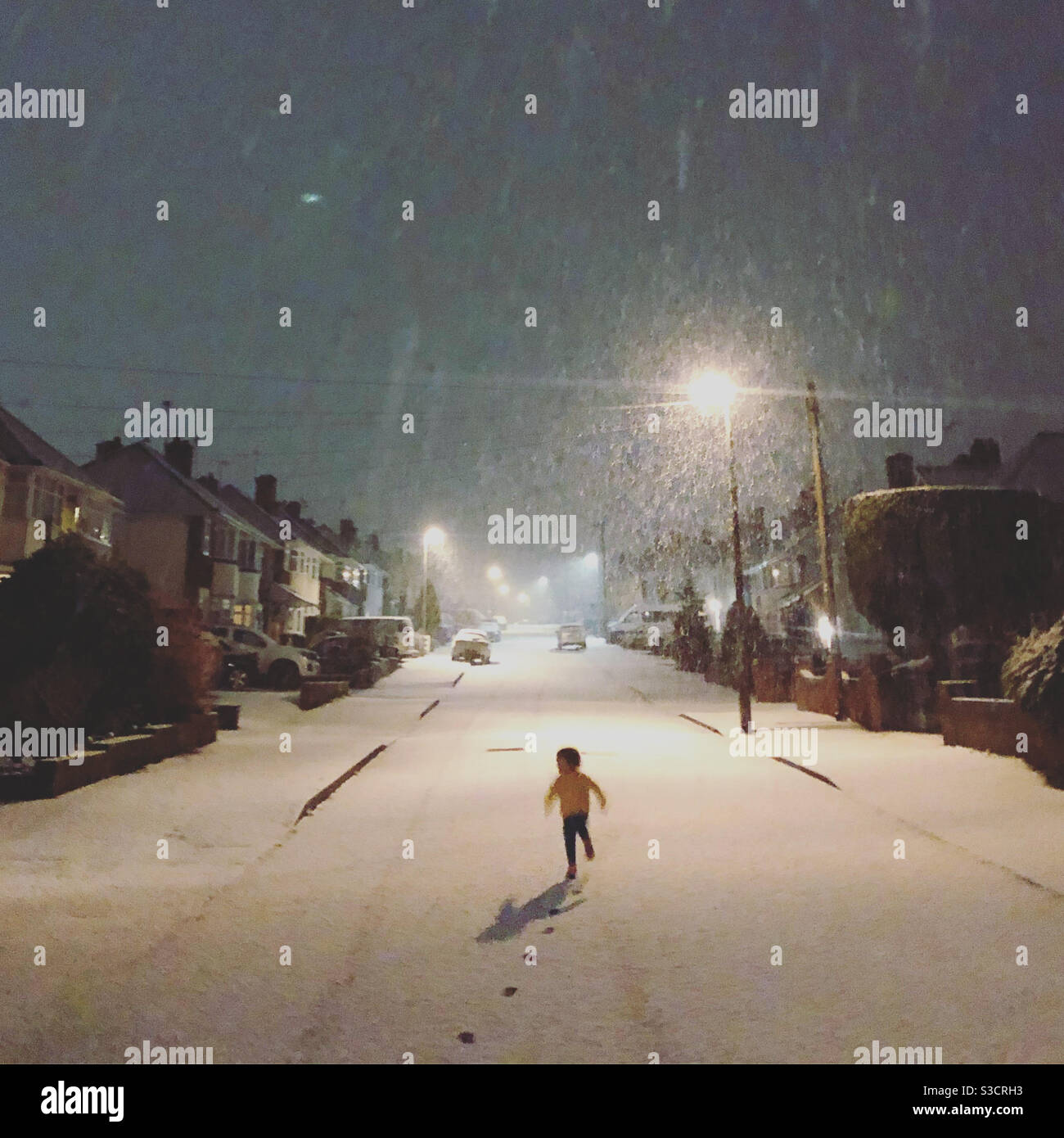Bambino che corre nella neve di notte Foto Stock