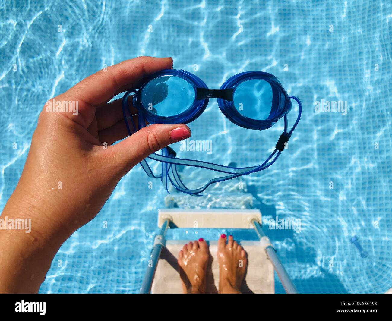 Donna che tiene gli occhiali di protezione sopra la piscina Foto Stock