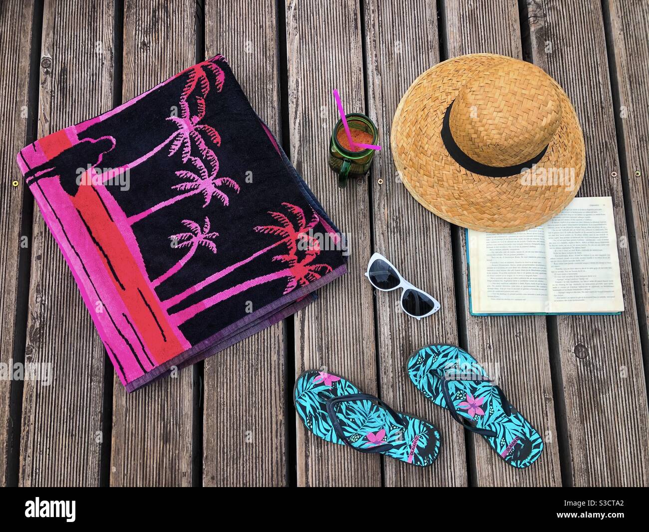 Disposizione degli appartamenti estivi: Asciugamano, infradito, occhiali da sole, cappello di paglia, cocktail e libro - Immagine stock catturata con smartphone