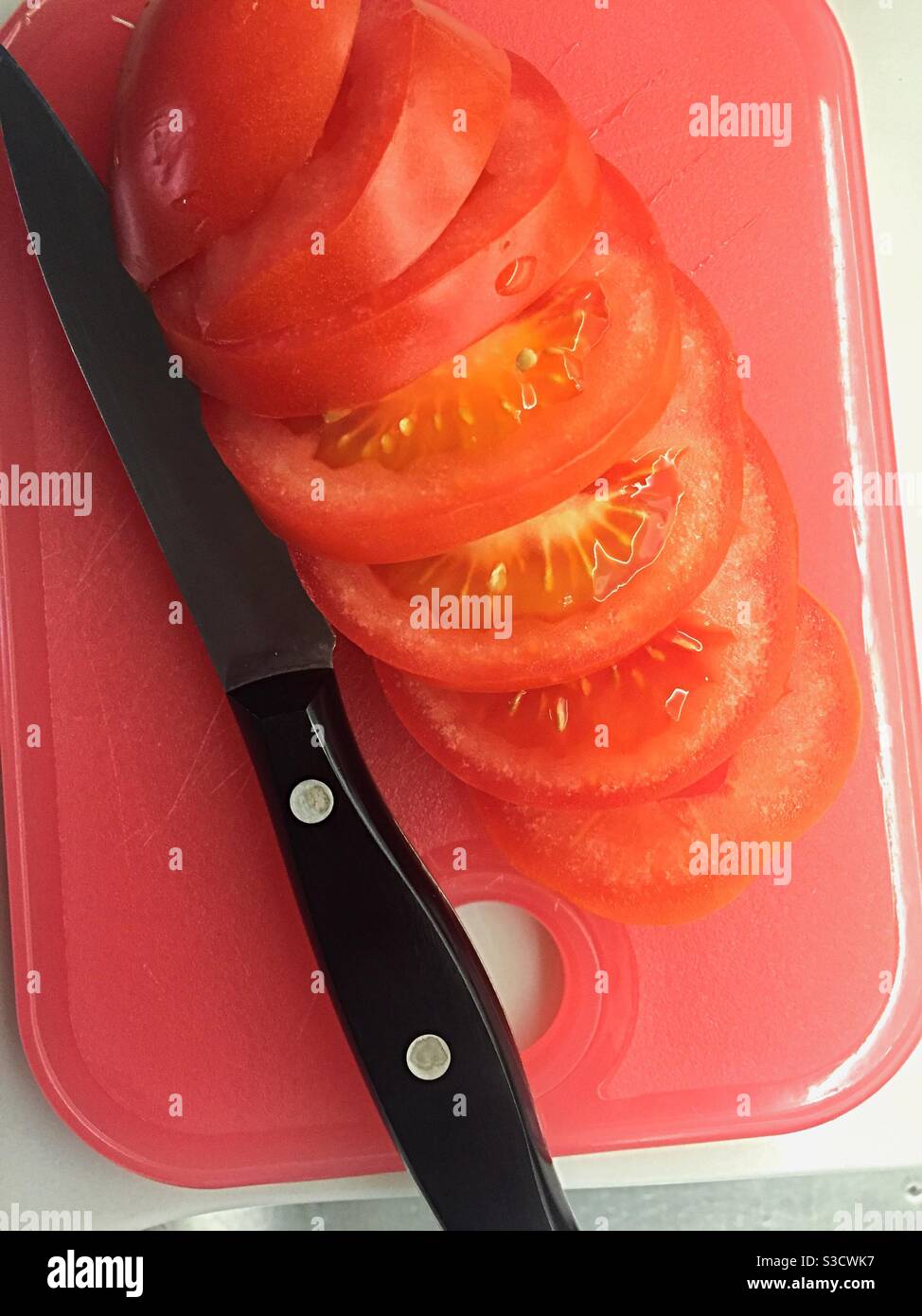 Primo piano di un pomodoro appena tagliato e coltello da parare su un tagliere da cucina residenziale, Stati Uniti Foto Stock