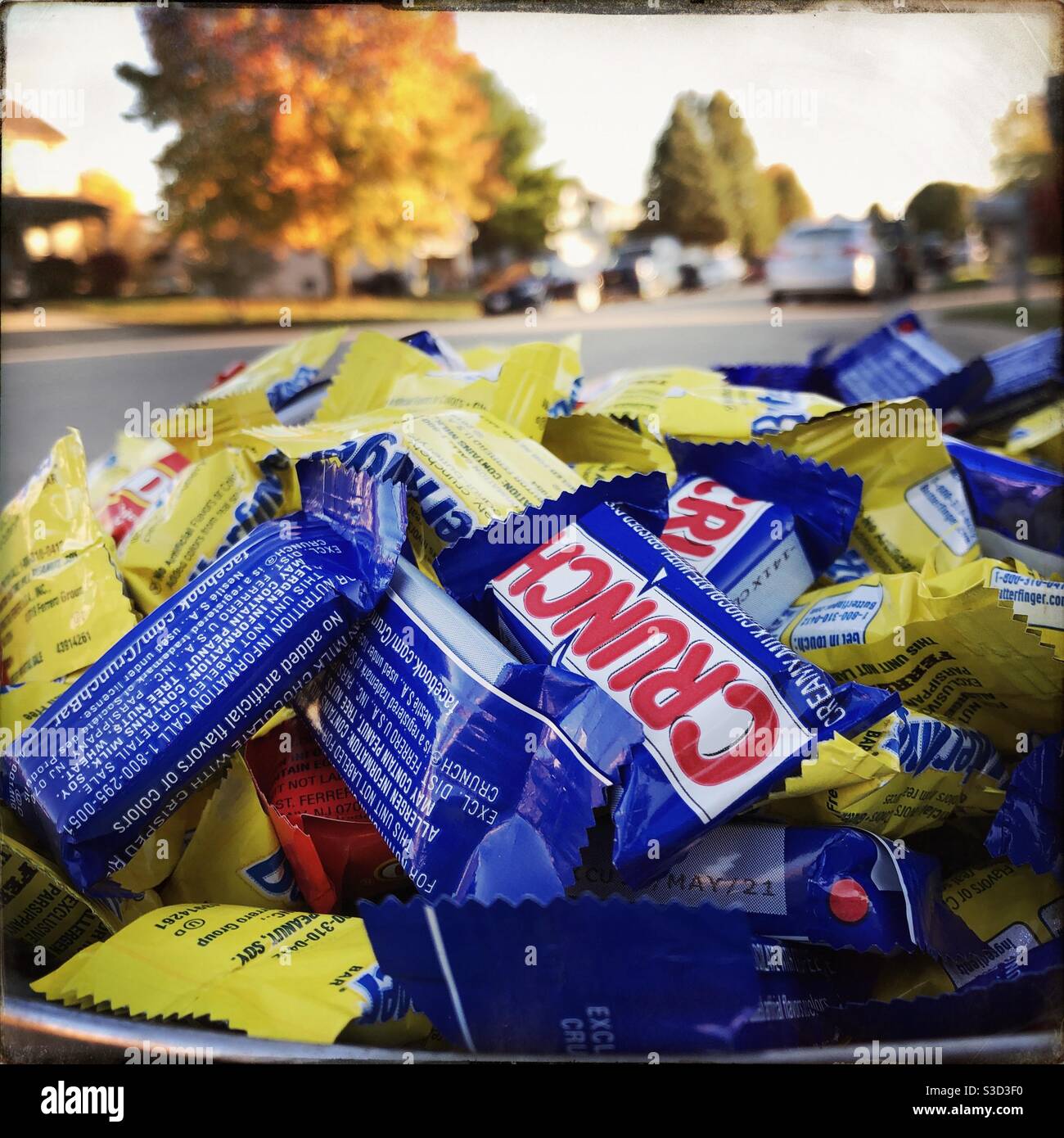 Una ciotola piena di barrette di caramelle al cioccolato pronte per il trucco o il trucco. Le barre del marchio incluse sono Butterfingers e Crunch. - Immagine stock catturata con smartphone