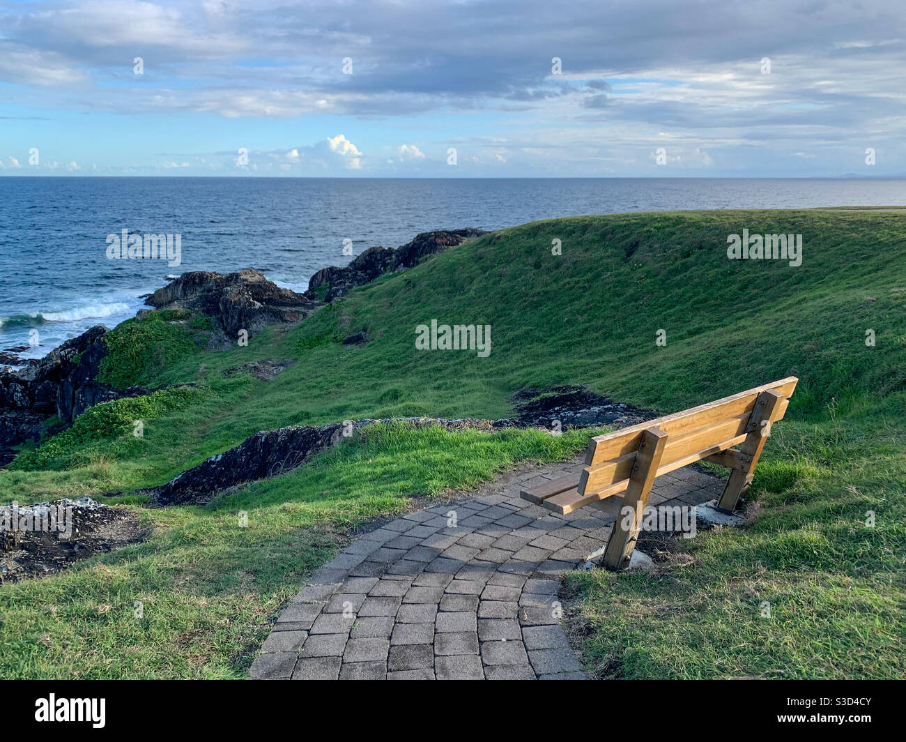 Contemplazione, aria fresca, un posto con vista oceano per invidia, bagnata nel tardo pomeriggio luce del sole di prima sera, mare blu, erba verde, Australia Foto Stock
