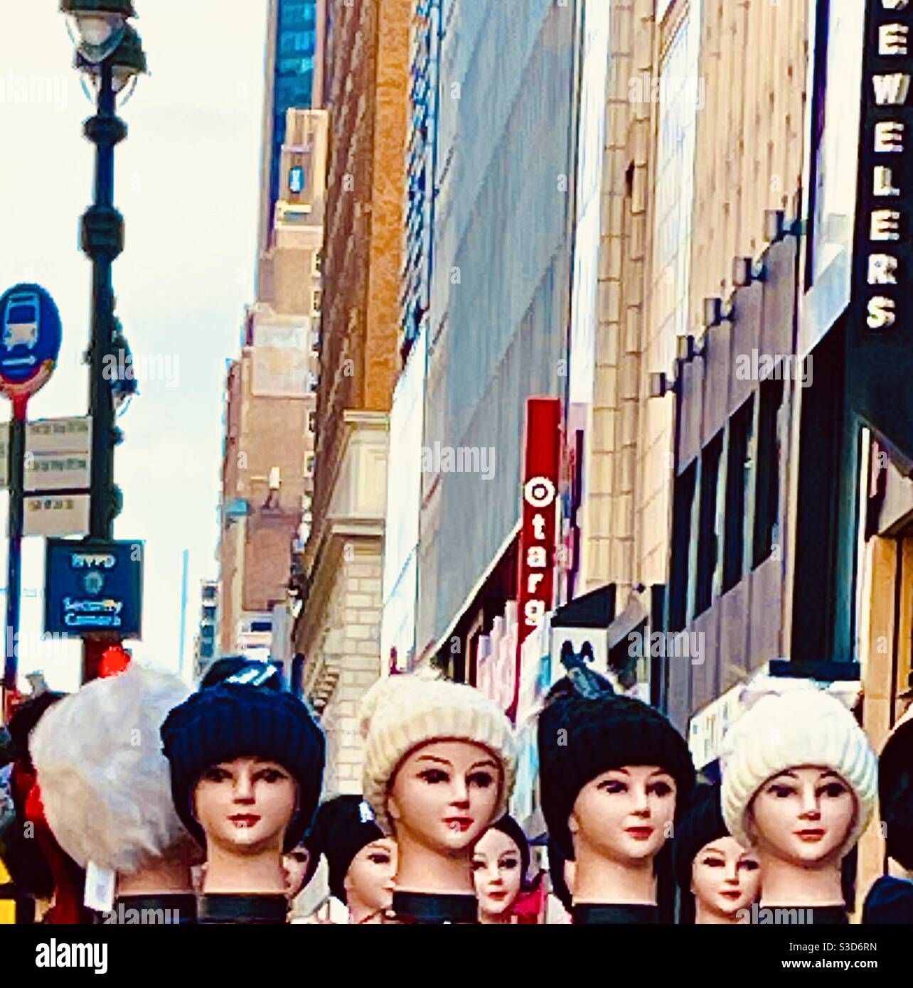 I cappelli in maglia con teste manichine danno l'impressione di donne che affollano il marciapiede sulla 34esima strada ovest di fronte a Macy's Herald Square, New York City, USA. Foto Stock