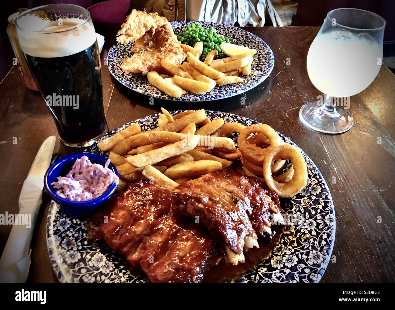 Costolette di ricambio, fish and chips e birra nera guinness in un pub inglese - Immagine stock catturata con smartphone