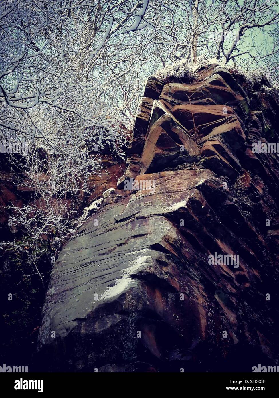 Una fotografia di una formazione rocciosa in cava in una mattinata invernale, con alberi coperti di neve Foto Stock