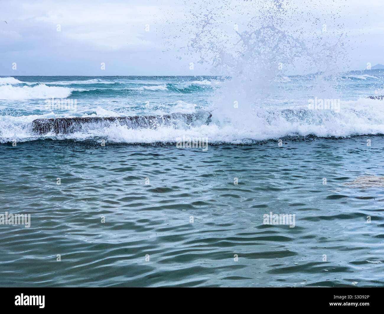 Onde che esplodono sul bordo della piscina di roccia creando un enorme spruzzi. Orizzonte e Oceano Pacifico sullo sfondo Foto Stock