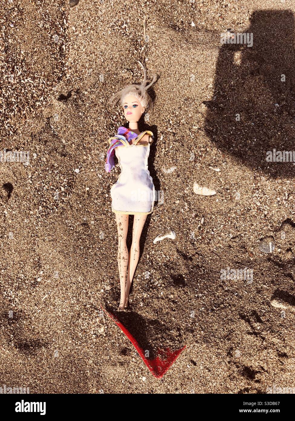 Bambola di plastica trovata sulla spiaggia di sabbia - Immagine stock catturata con smartphone