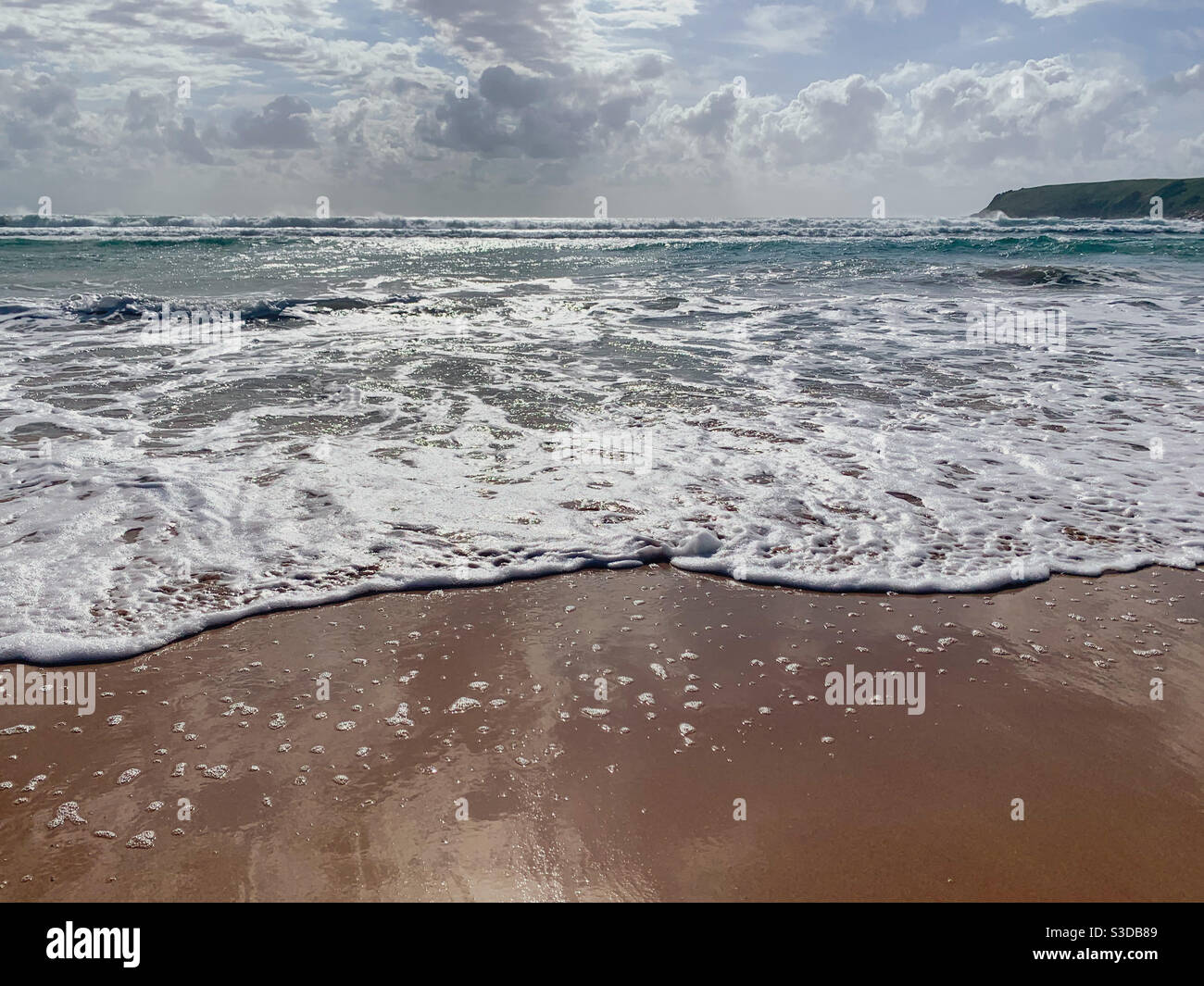 Nuvole riflesse nella sabbia bagnata della spiaggia lucida, giorno nuvoloso Foto Stock