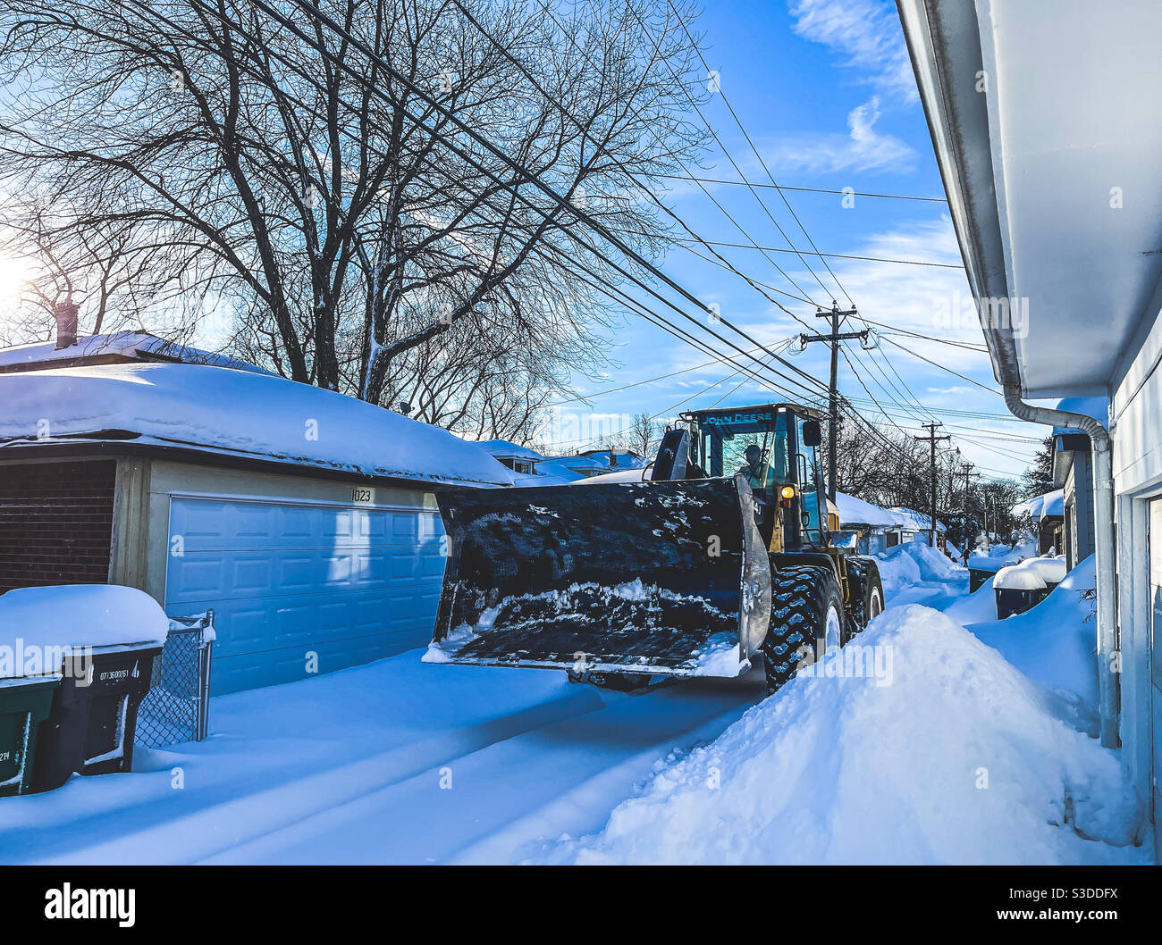 Oak Park, Illinois, Stati Uniti. 16 febbraio 2021. Un caricatore frontale passa attraverso un vicolo dopo quasi 24 ore di neve pesante in questo sobborgo occidentale di Chicago. La caduta di neve ha totalizzato oltre 12 pollici/25cm. - Immagine stock catturata con smartphone