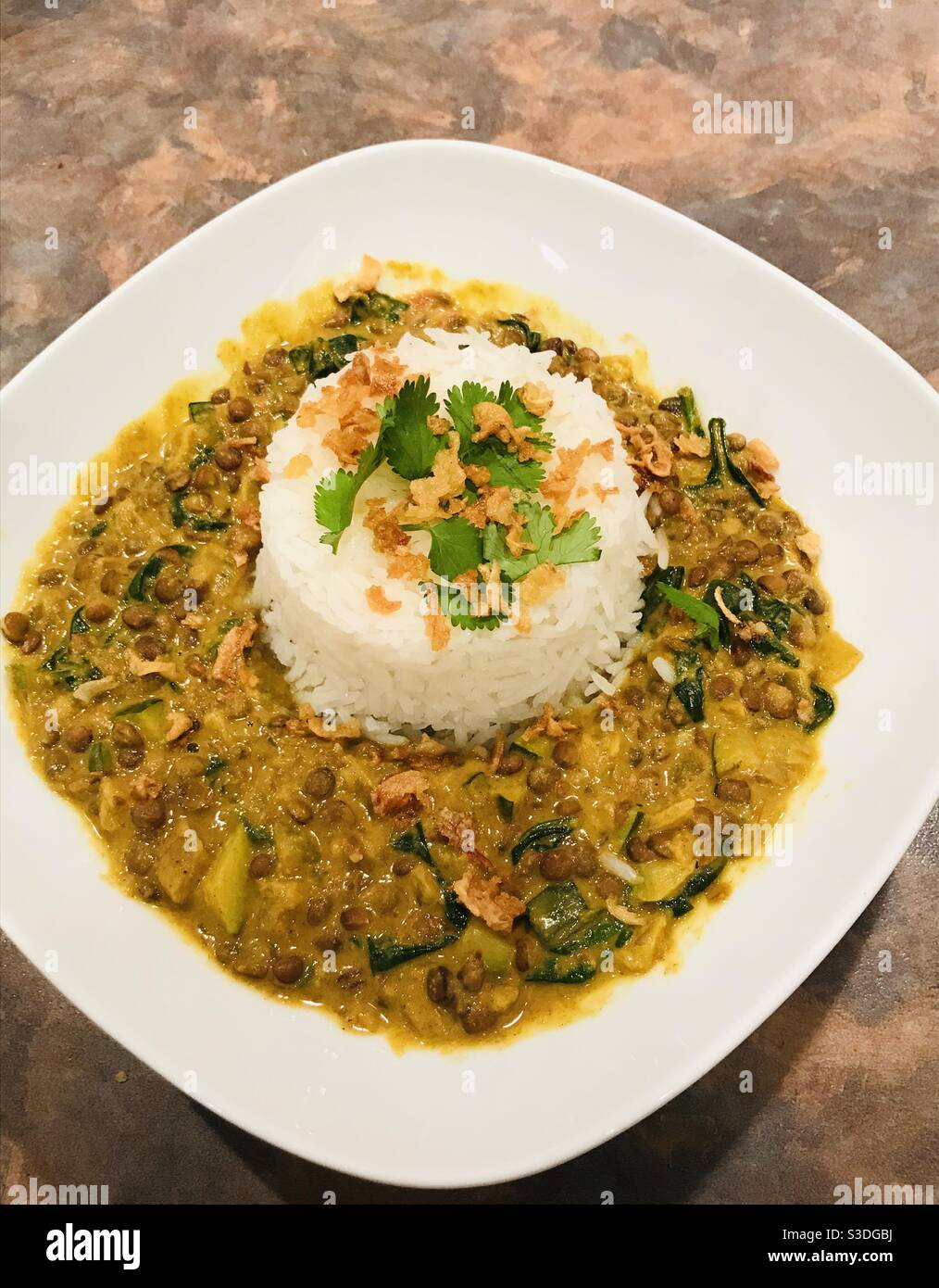 Ciotola di curry vegetale di lenticchie con riso basmati. - Immagine stock catturata con smartphone