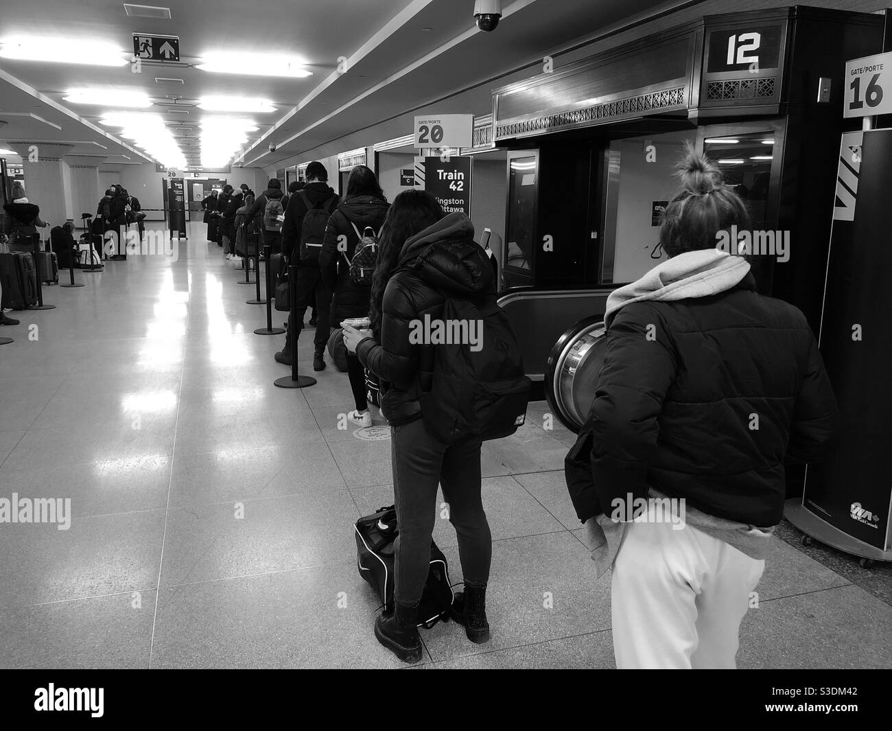I passeggeri che formano una linea distanziata prima di salire a bordo del treno presso la Union Station di Toronto, Ontario, Canada, durante la pandemia COVID-19, febbraio 24; 2021 - Immagine stock catturata con smartphone