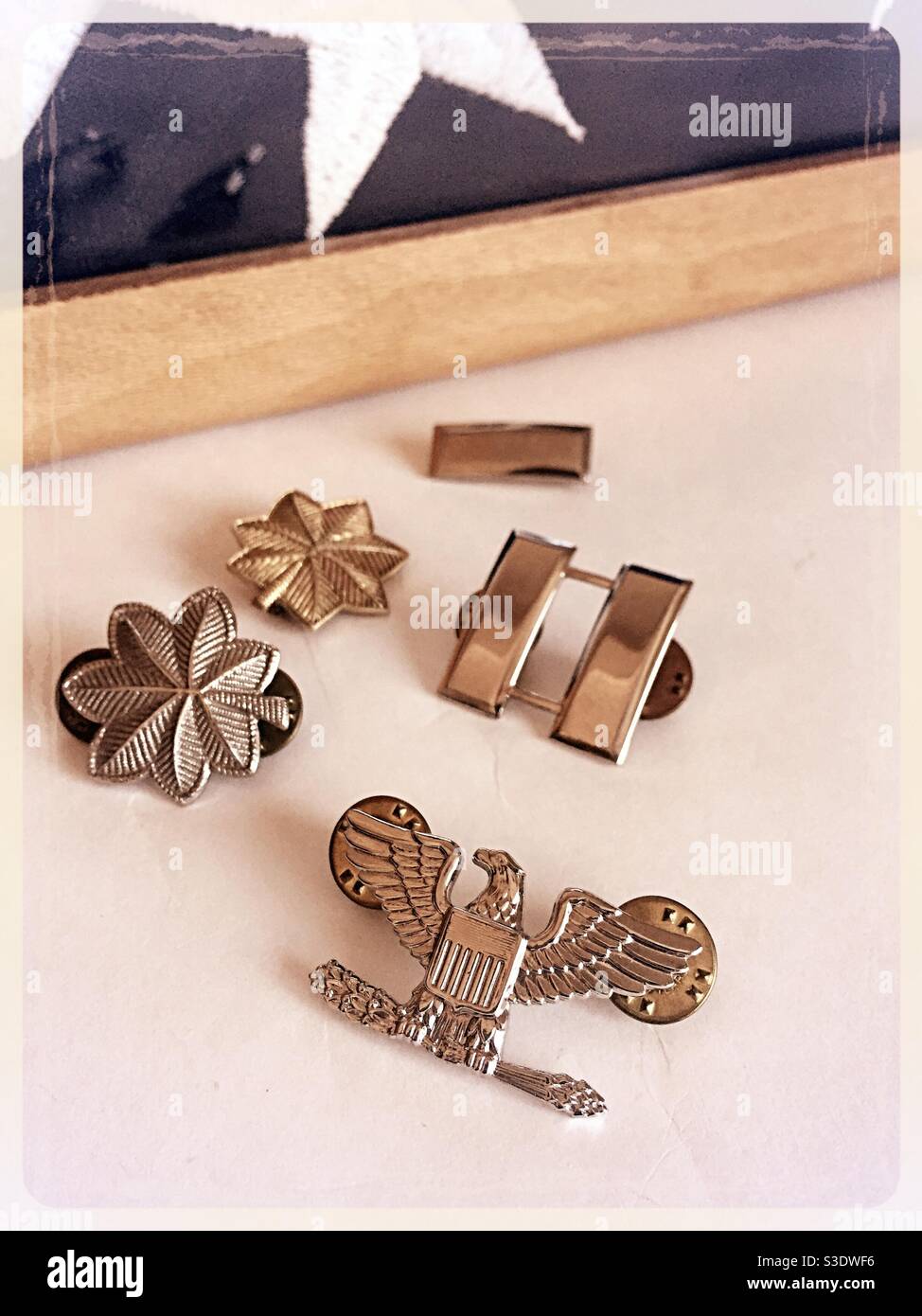 Primo piano delle insegne militari statunitensi di fronte a una bandiera commemorativa dei veterani ripiegati, USA - Immagine stock catturata con smartphone