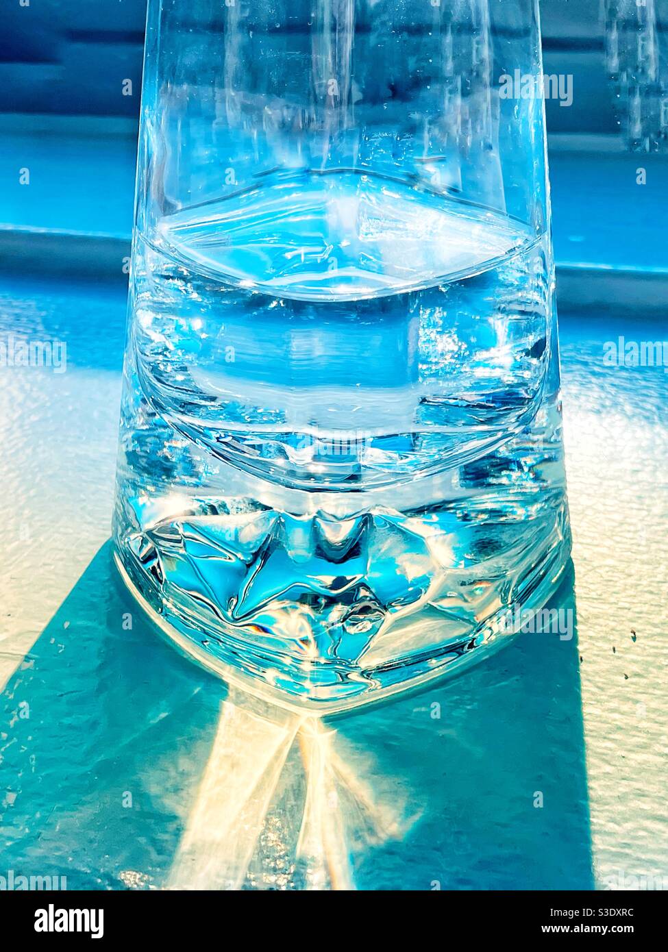 Riflessi in un bicchiere d'acqua; mezzo vuoto o mezzo pieno? Foto Stock