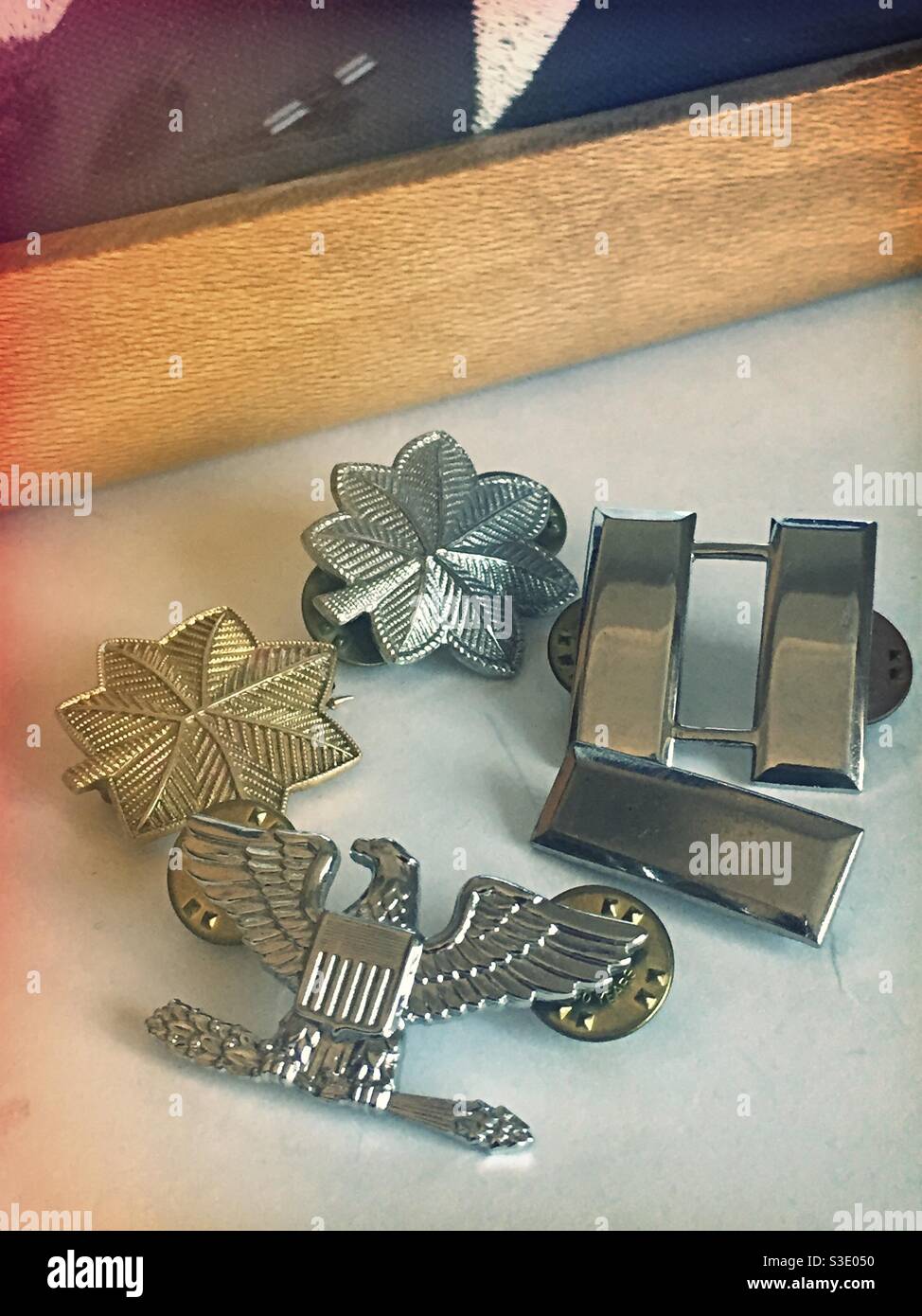 Ancora vita di insegne militari statunitensi di grado dal primo tenente al colonnello da un ufficiale di carriera di fronte ad una bandiera ripiegata, USA - Immagine stock catturata con smartphone