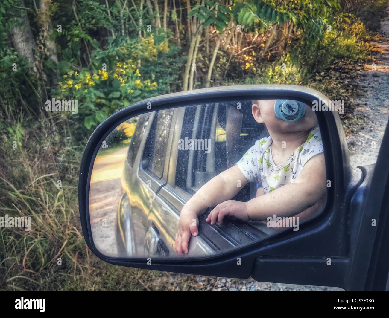 Il bambino ha visto nello specchio, guardando fuori la finestra lungo la corsia Foto Stock