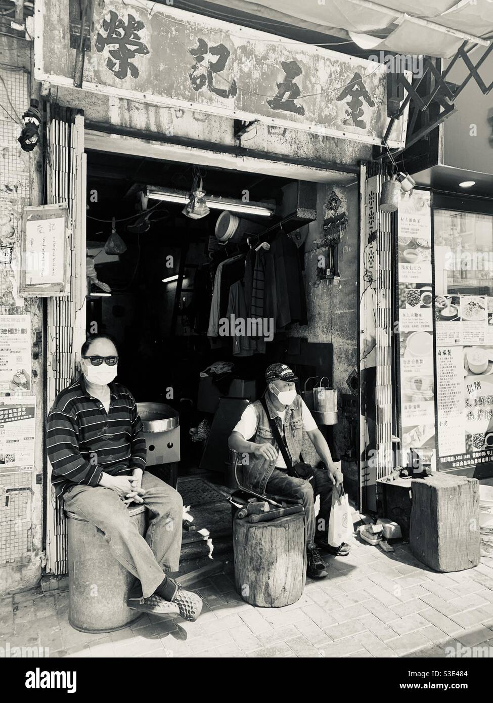 Uomini cinesi seduti al di fuori di un piccolo negozio nel mercato di AP Lei Chau, Hong kong. Foto Stock