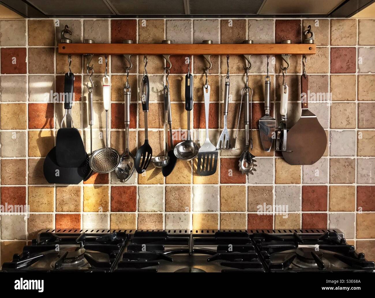 Cucina in stile rustico con piano cottura a grande scelta e rack di utensili. Foto Stock