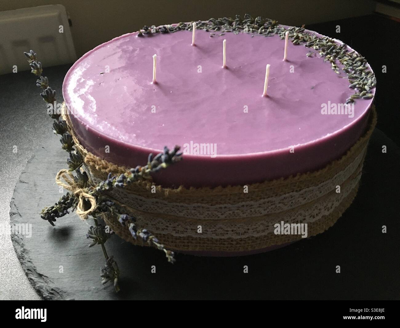 Candela di lavanda viola di cera di soia biologica fatta in casa decorata con secco lavanda e un nastro di spago Foto Stock