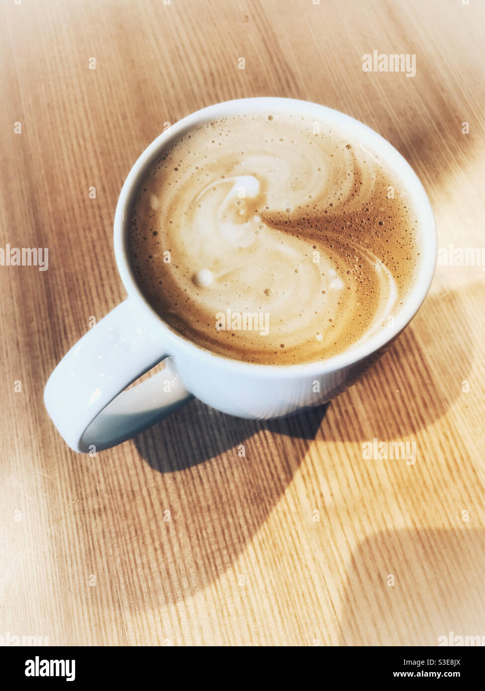 Caffè latte o cappuccino in tazza bianca su un tavolo di legno. - Immagine stock catturata con smartphone