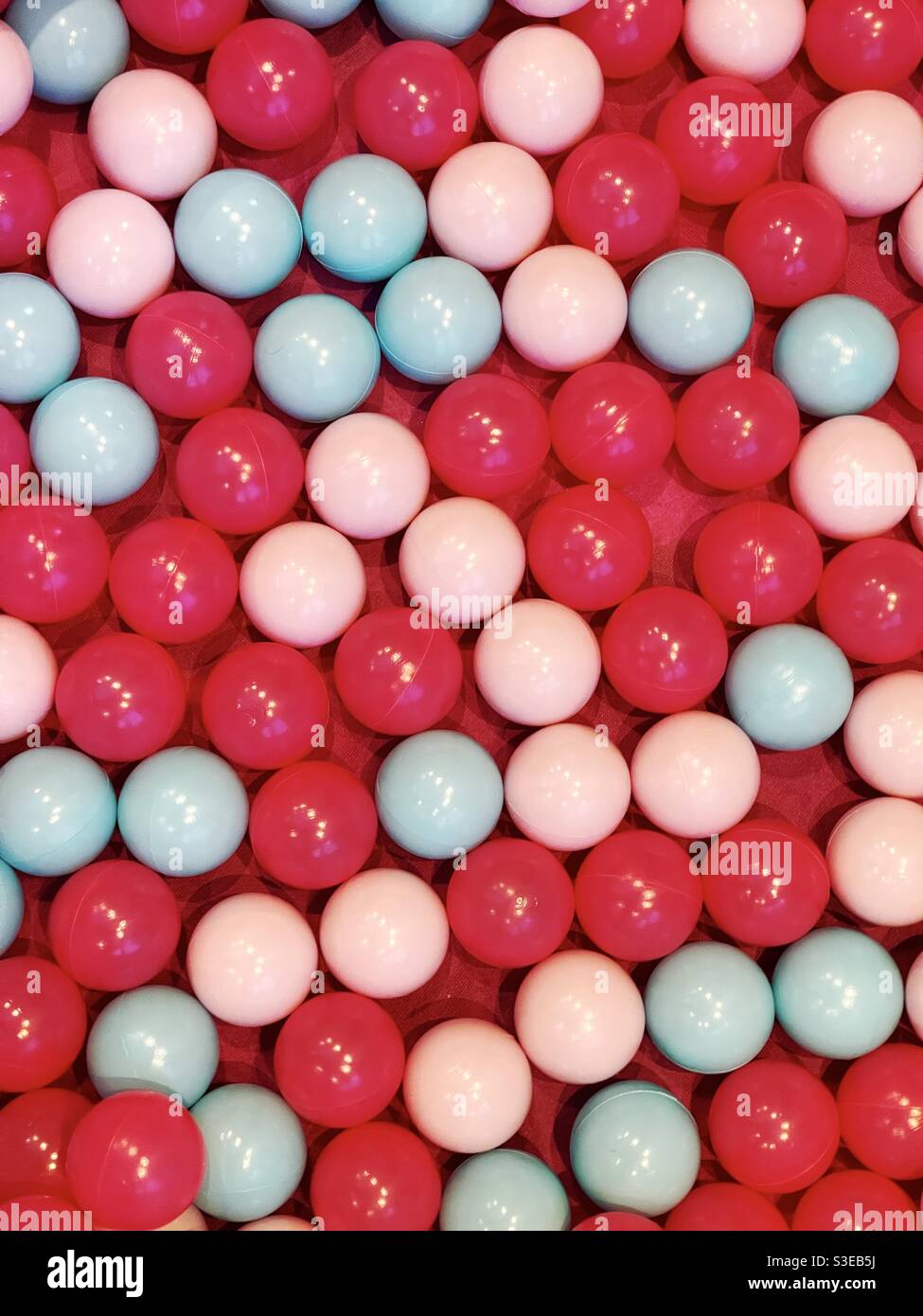 Palline giocattolo di plastica in rosso, bianco e blu in un laghetto di palla Foto Stock