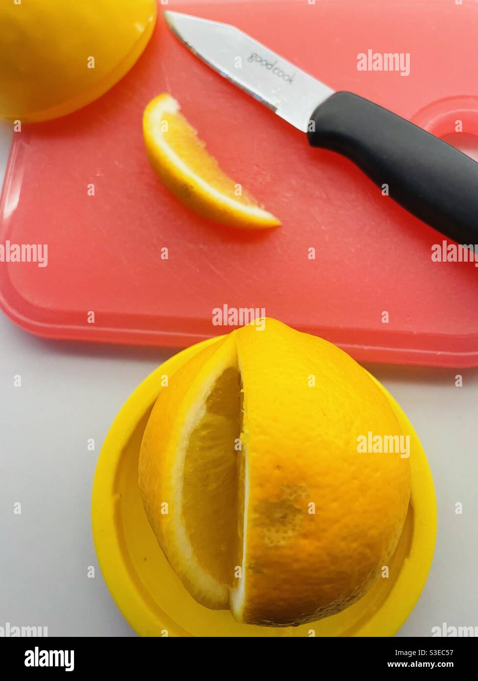 Primo piano di un limone Meyer a fette su un arancio tagliere con un coltello di taglio pericoloso Foto Stock
