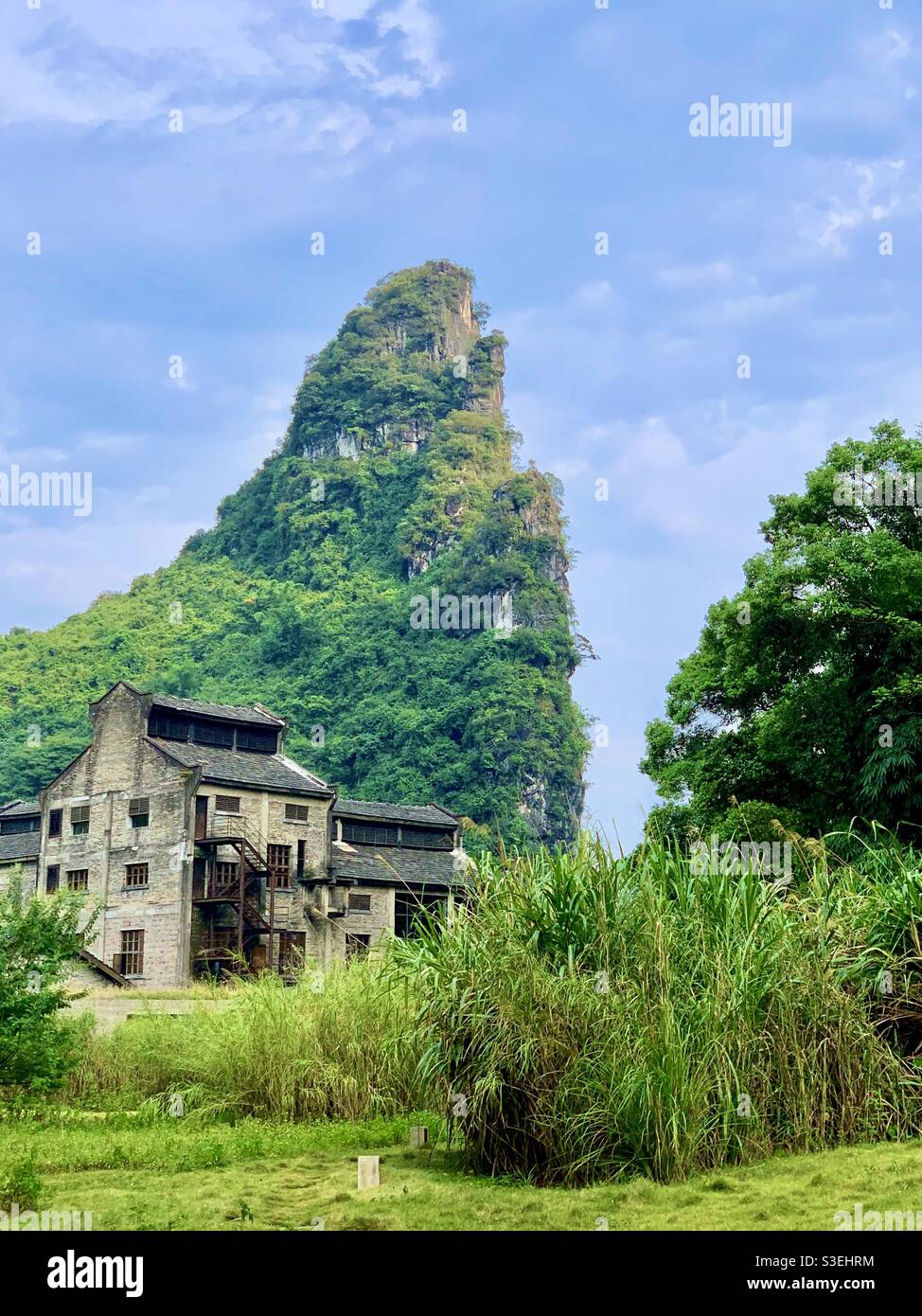 Alta montagna con casa vecchia e rotta sotto il bel cielo blu a Yangshuo, Guangxi, Cina. Foto Stock