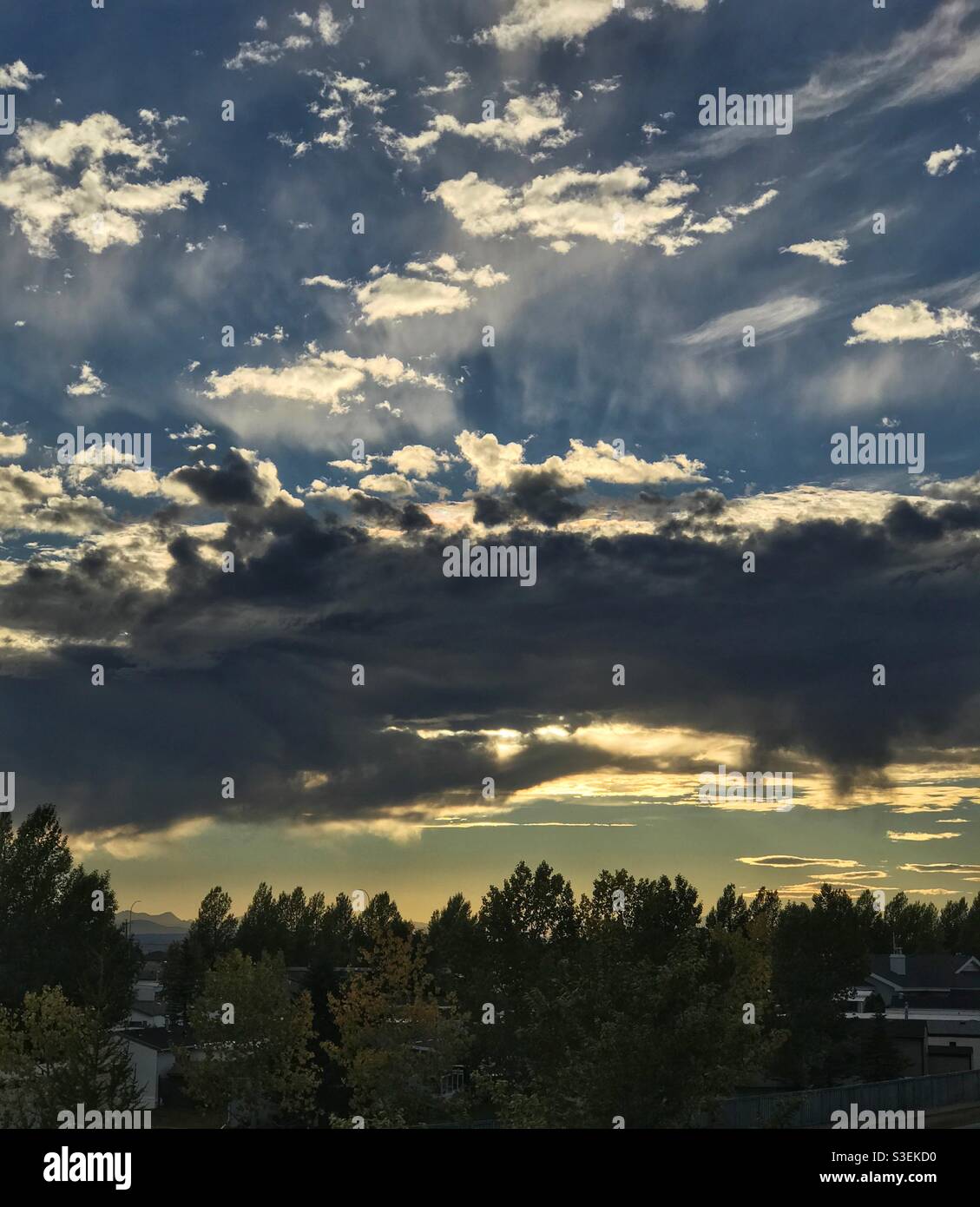 Raggi solari che illuminano le nuvole, appena prima del tramonto. Calgary, Alberta, Canada. - Immagine stock catturata con smartphone