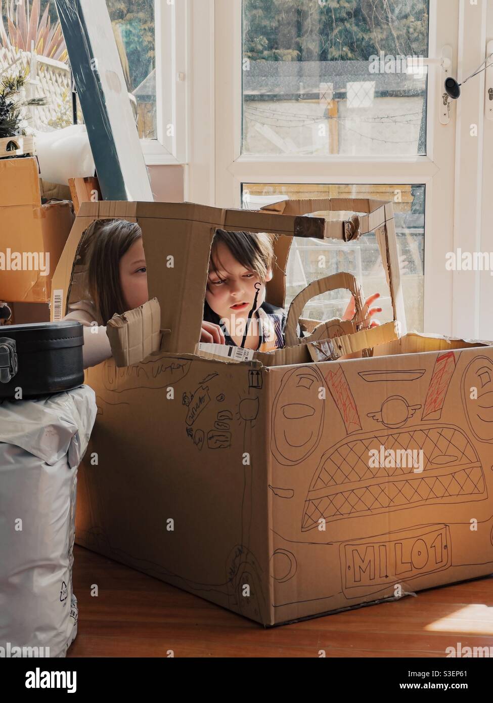 Bambini che giocano in un box auto di cartone Foto Stock